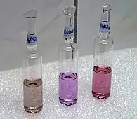 日光灯下的钕化合物溶液,从左到右分别为硫酸钕、硝酸钕和氯化钕。